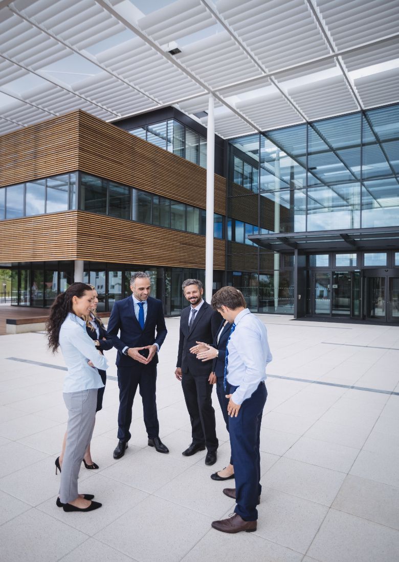 Group of cheerful businesspeople interacting outside office building